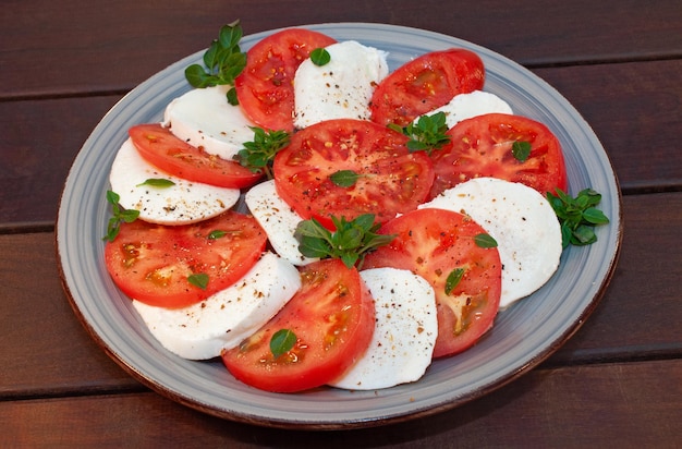 A plate of mozzarella, tomato, and parsley salad