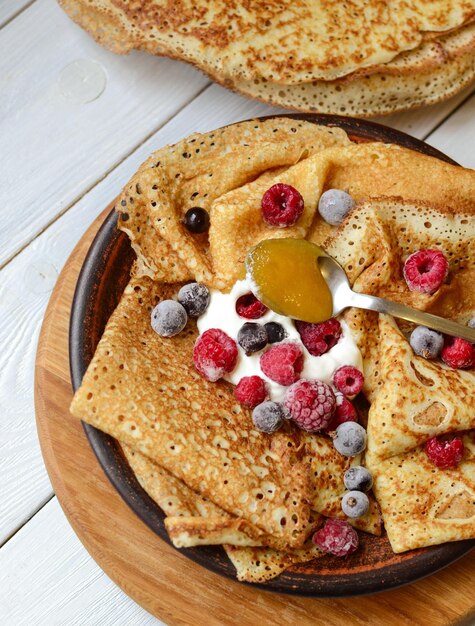 A plate of pancakes with berries and cream on top