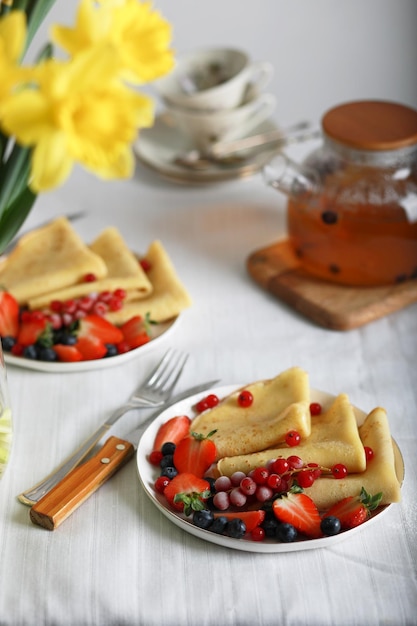 A plate of pancakes with berries and strawberries on a table.