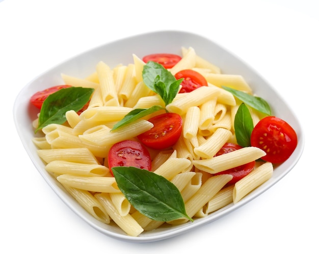 Plate of pasta with cherry tomatoes and basil leaves isolated on white