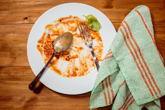 Piatto di pasta al sugo finito e sporco su un tavolo di legno. vista dall'alto