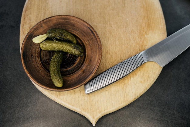 Plate of pickled homemade cucumbers on wooden desk Top view