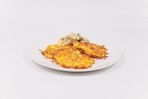 A plate of potato pancakes decorated with basil leaves on the table.