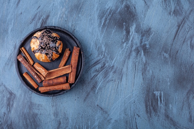 Plate of profiteroles and cinnamon sticks and glass of tea on blue.