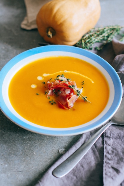 A plate of pumpkin soup with a jamon, garlic, thyme and cream