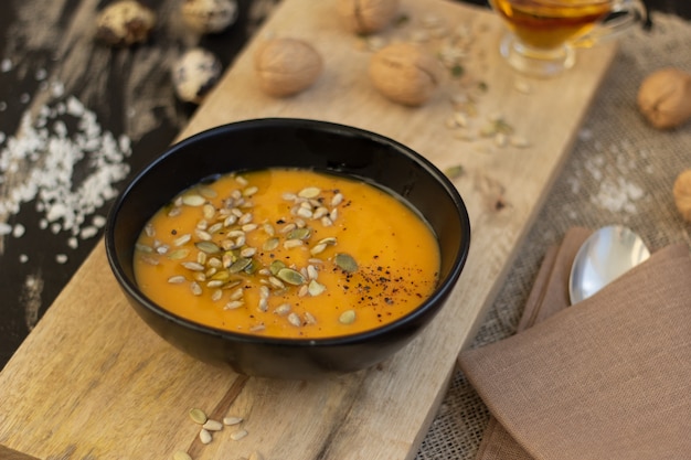 Plate of pumpkin soup on wooden cutting board