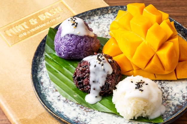 Photo a plate of purple sticky rice balls with mango on it.