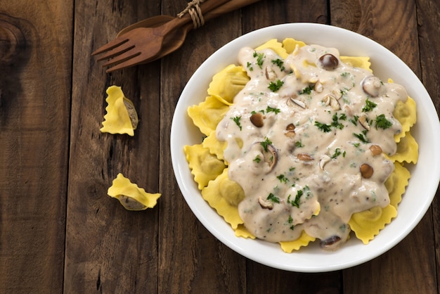 Plate of ravioli with cream sauce on wood table