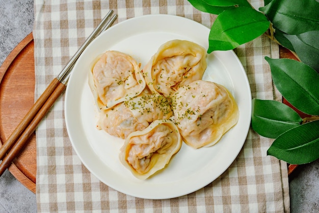 Photo a plate of ravioli with green leaves on a tablecloth.