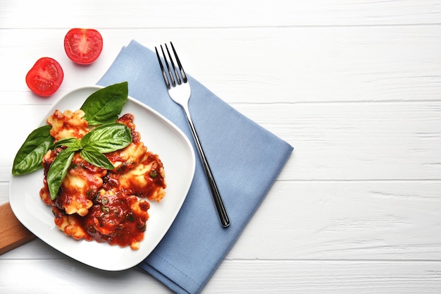 Plate of ravioli with tomato sauce on table