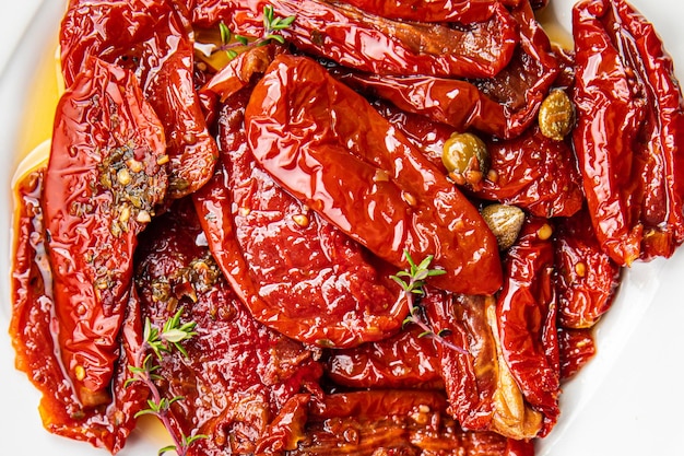 A plate of red peppers with a sprig of rosemary on the side.