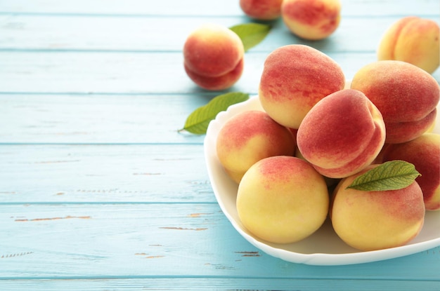 Plate of ripe peaches on blue background