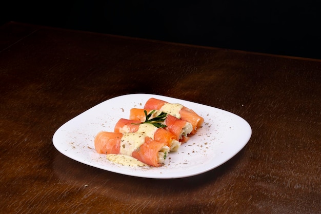 Plate of rolled salmon stuffed with cream cheese and parsley angle view on wooden table