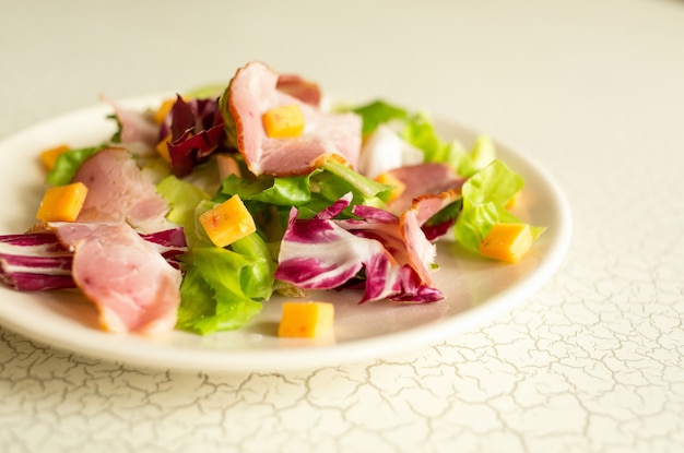 Plate of salad of green leaves, ham and cheese