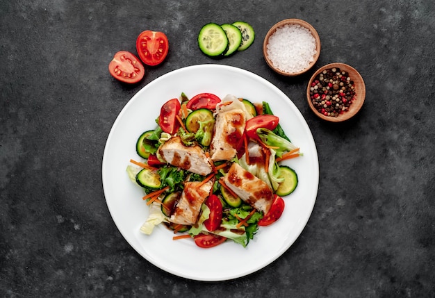 a plate of salad of tomato, chicken, cucumber, carrots, soy sauce in a plate