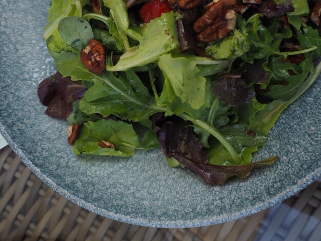 A plate of salad with a bunch of pecans on it