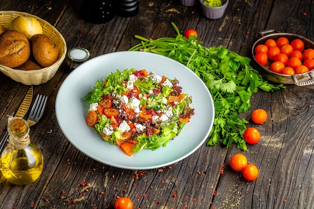 Photo on a plate, salad with cheese, baked pepper, herbs, vegetables, sauce