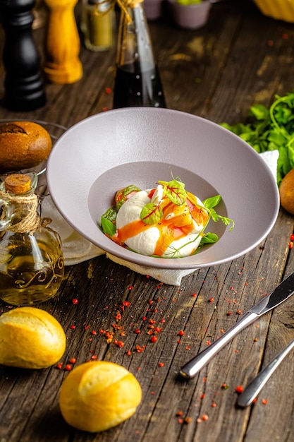 on a plate, salad with italian fresh cheese, buratta, basil, tomatoes, greens