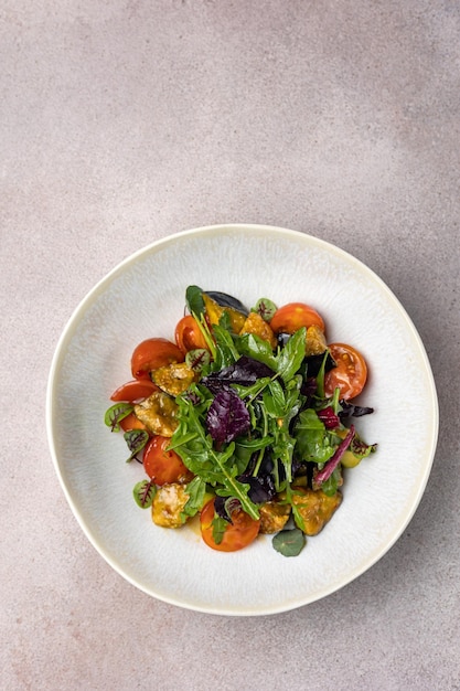 A plate of salad with tomatoes and greens