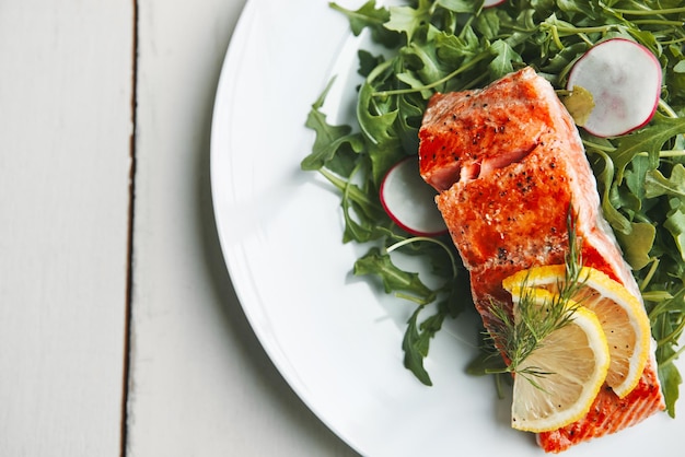 plate salmon or fish with lemon above and salad for health wellness and nutrition to lose weight in home food dinner or lunch with fruit brunch and vegetables for diet seafood and healthy meal
