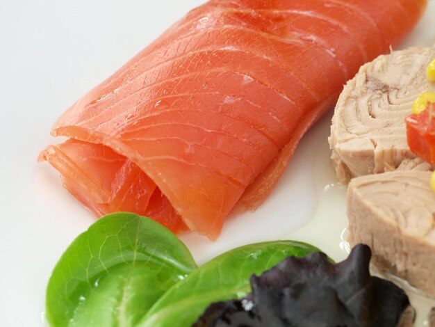 Photo a plate of salmon on a table with lettuce and lettuce.