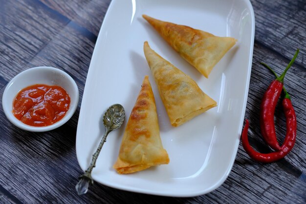 A plate of samosas with a spoon next to it