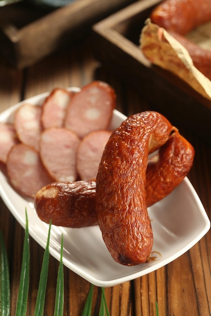 A plate of sausages on a table with a basket of bread in the background.