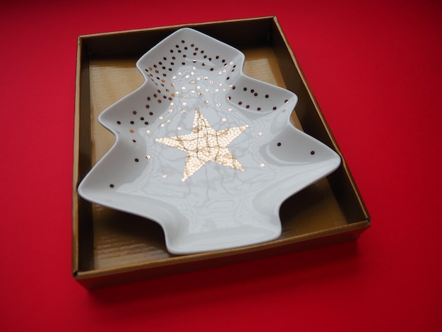 Photo a plate in the shape of a christmas tree with gold ornaments and a star in the middle gift