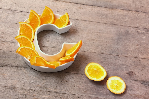 Photo plate in shape of letter c with orange slices on wooden background