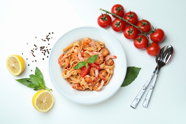 Plate of shrimp pasta and ingredients on white