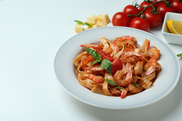 Plate of shrimp pasta and ingredients on white