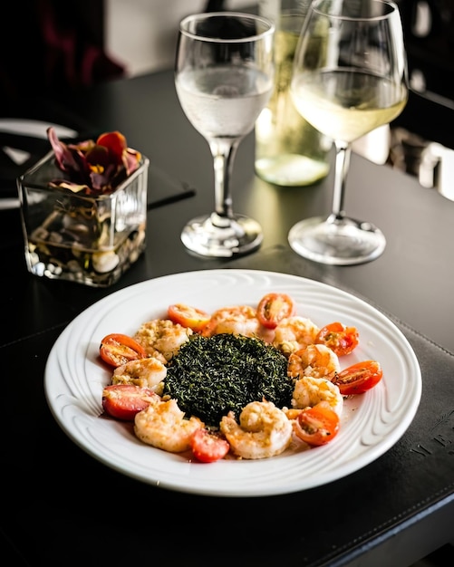 A plate of shrimp and spinach with a glass of wine on the table.