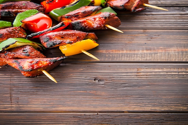 A plate of skewers with meat and vegetables on a wooden table