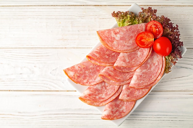白い木製の背景にスライスされた豚肉のハムプレート