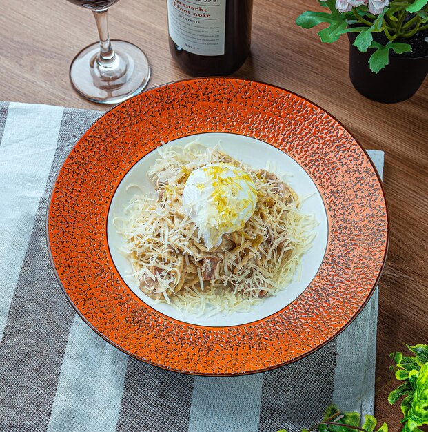 A plate of spaghetti with a scoop of ice cream on it next to a glass of wine