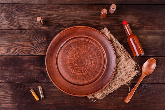 Plate, spoon, spices and other kitchen accessories on a dark wooden background