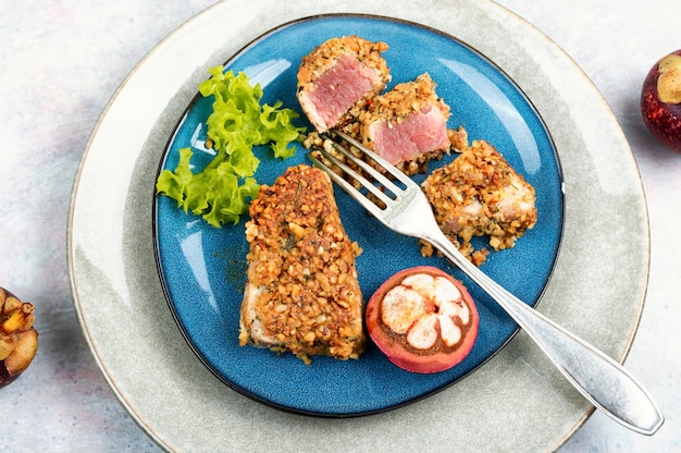 Plate of steak of baked tuna in a nut panic with mangosteens Flat lay