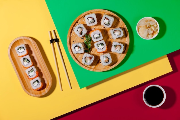 A plate of sushi with a cup of soy sauce and a chopstick.