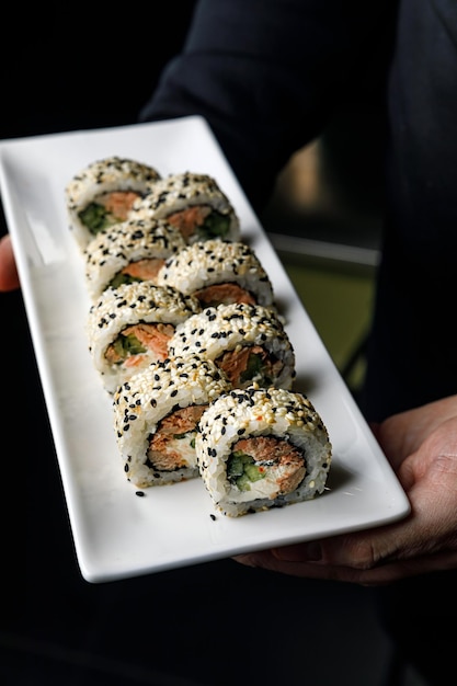 A plate of sushi with a sesame seed roll on top