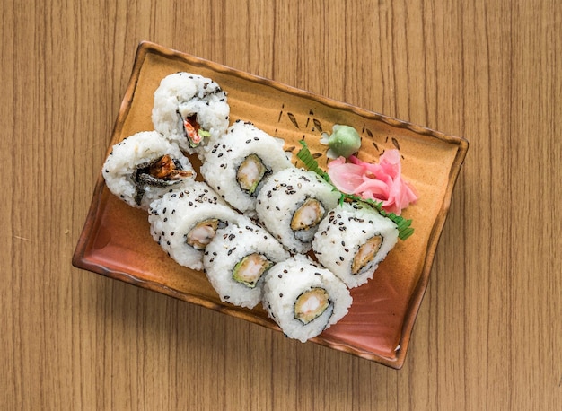 A plate of sushi on a wooden table ebi maki rollSalmon sushi rolls