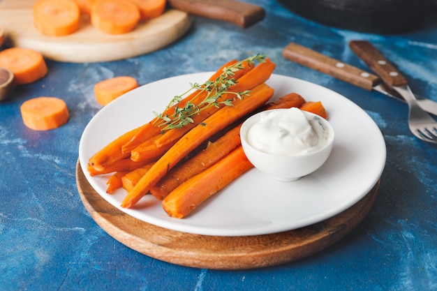 Plate of tasty baked carrot on color space