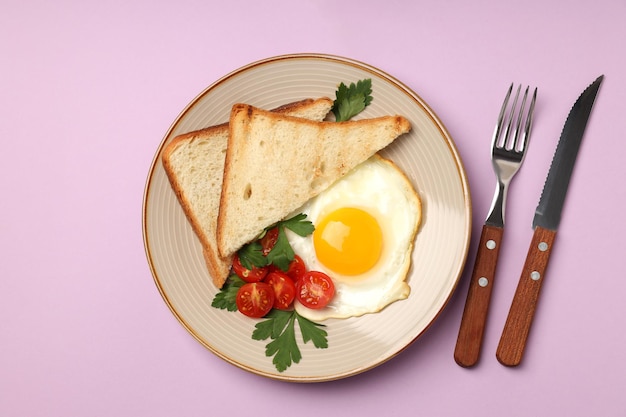 Plate of tasty breakfast on violet background