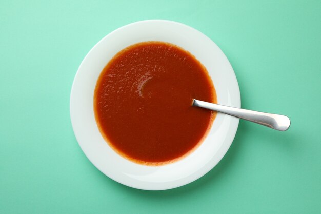 Plate of tasty tomato soup and spoon on mint