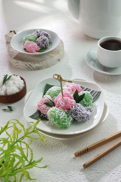 A plate of thai desserts with a cup of coffee and a banana leaf.