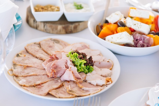 A plate of turkey and salad with a bowl of feta cheese.