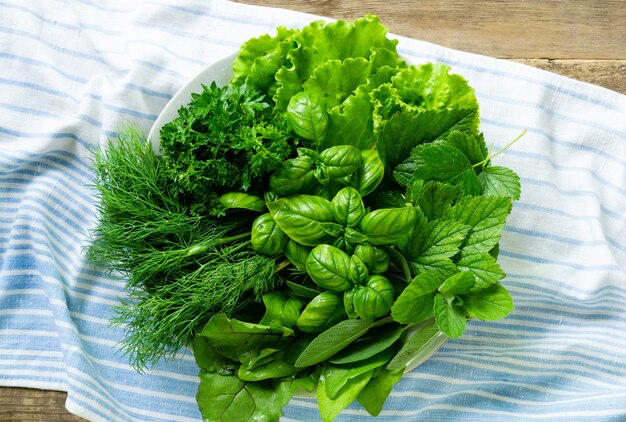 Plate of various fresh greens on a textile background