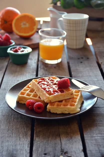 Plate of waffles with raspberry marmalade, orange juice and coffee