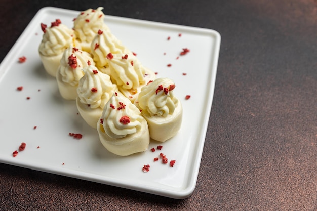 A plate of white chocolate truffles with a red sprinkle of sprinkles.