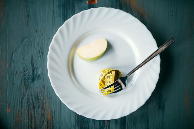 Plate with apple and measuring tape, weight loss