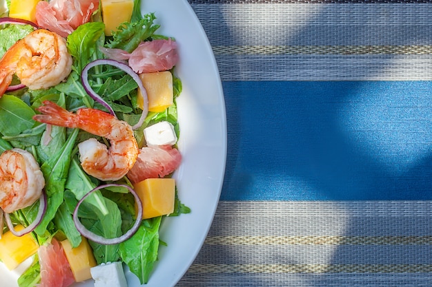 Plate with asian salad with shrimp, mango and pomelo